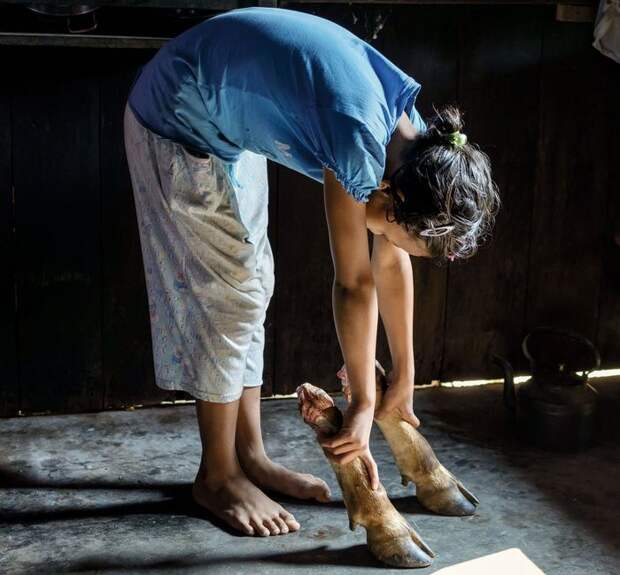 12-летняя Беслинда Кхонгдуп держит в руках коровьи ноги, из которых кхаси варят суп. Хотя большинство индийцев является индуистами, и коровы для них священны, жители Маулиннонга - христиане и, следовательно, могут есть говядину.
