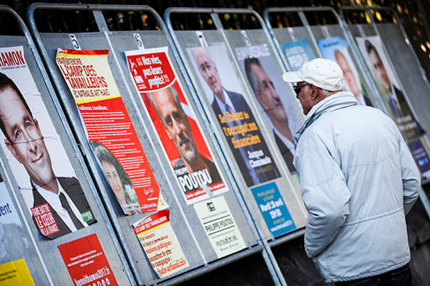 A man looks at campaign posters of the 11th candidates who run in the 2017 French presidential election in Enghien-les-Bains, near Paris, France April 19, 2017