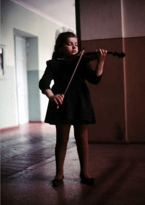 Девочка играет на скрипке в коридоре