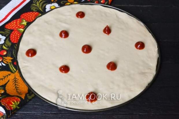 Положить на тесто томатный соус