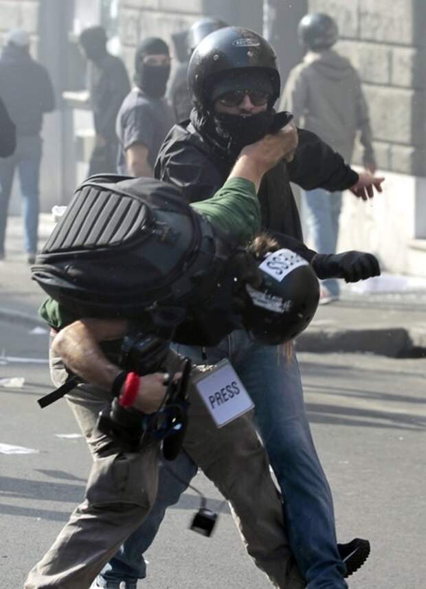 A demonstrators hits a photojournalist during a demonstration of the 'Indignant' group against banking and finance in Rome