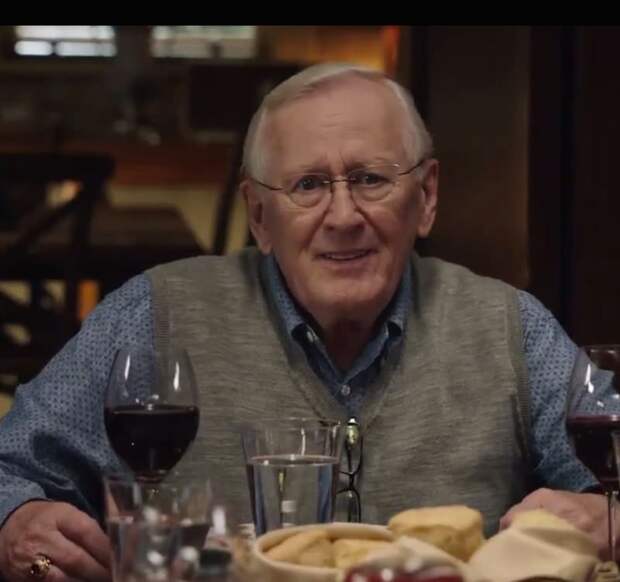 Blue Bloods Henry Reagan sitting at the family dinner table with a glass of wine in front of him