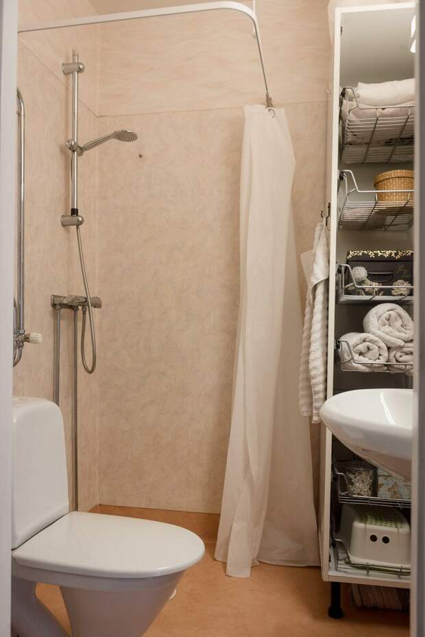 Ванная комната без изысков. Раковина, открытый душ со шторкой и удобный стеллаж для хранения всех ванных принадлежностей