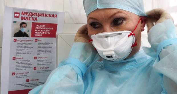 Сотрудница Центра гигиены и эпидемиологии надевает защитную медицинскую маску 