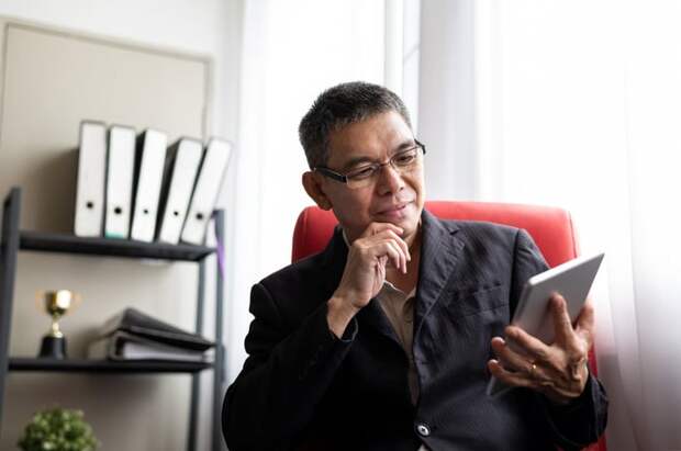 Smiling person looking at tablet in office.