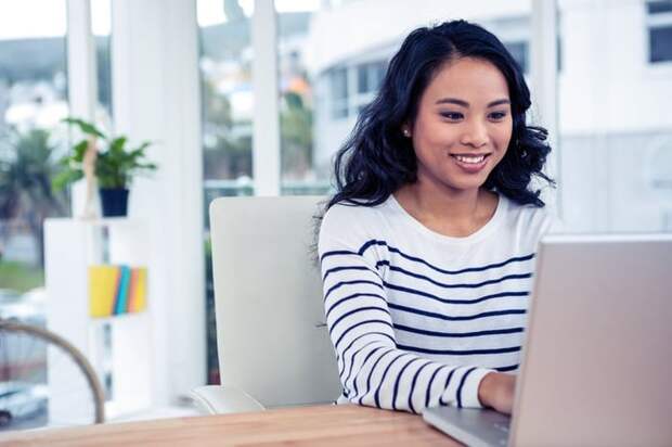Woman using laptop and smiling.