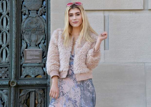 Smirking in pink aviator sunglasses and pink faux fur coat