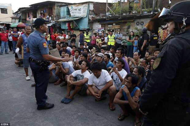 Жители города Pasig недалеко от Манилы сидят на земле, а филиппинский полицейский разговаривает с ними о наркотиках   дутерте, филиппины против наркотиков