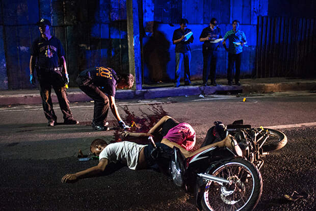 MANILA, PHILIPPINES - OCTOBER 3: (EDITORS NOTE: Image contains Graphic Content) Police investigators examine the bodies of two men who died in an alleged shootout with police on October 3, 2016 in Manila, Philippines. The Duterte administration shifted to the next phase on its war on drugs after the first 100 days of President Rodrigo Duterte as over 3,700 people have been killed while more than 700,000 drug dependents surrendered to authorities. According to reports, Duterte received an 'excellent' rating for his war on drugs during a recent opinion, with 84 percent of Filipinos respondents said they are satisfied with the drug crackdown. 