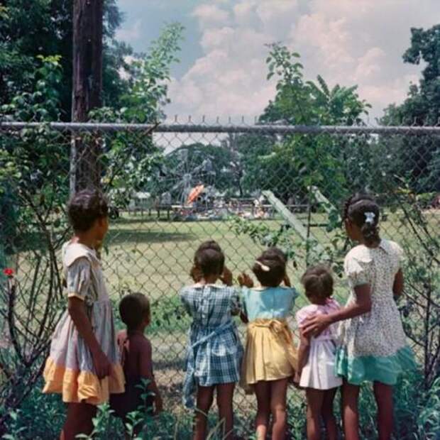 Чернокожие дети у забора детской площадки “только для белых”, Алабама, 1956.