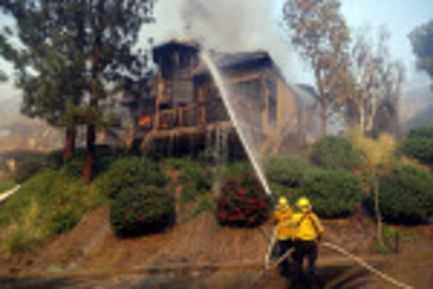 Firefighters hose down a burning home, in Westlake Village, Calif California Wildfires, Westlake Village, USA - 09 Nov 2018