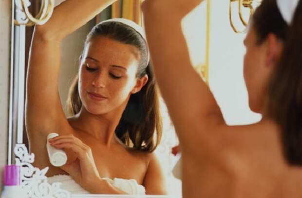 Young woman applying deodorant, reflection in mirror