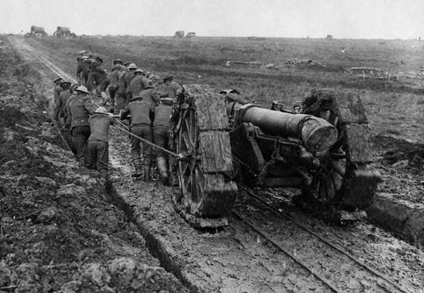 Солдаты тянут тяжёлое артиллерийское орудие по грязи.