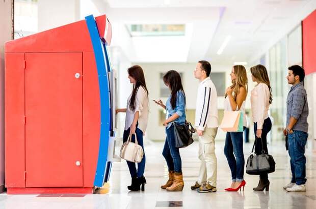 A long line of people at an ATM trying to withdraw money.