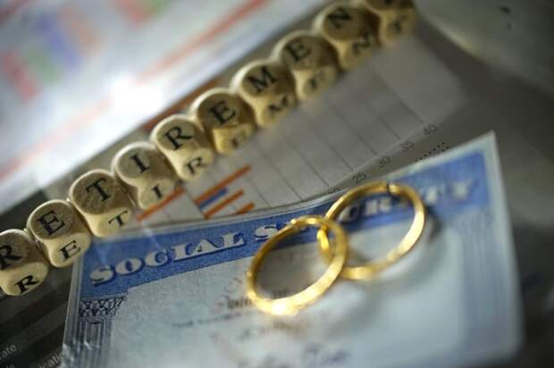 wedding rings sit atop a Social Security card with cubes in the background with letters on them spelling out retirement