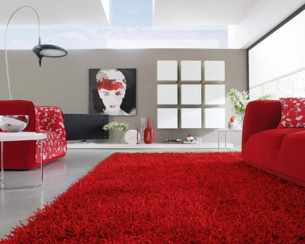 эффектная гостиная с ярко красным ковром на полу и красными диванами