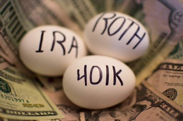 Three eggs lying on a stack of American dollars. One egg reads 401k, while the other two read IRA and Roth.