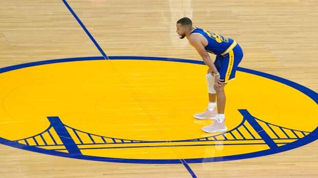 Steph Curry standing on Golden State Warriors halftime logo