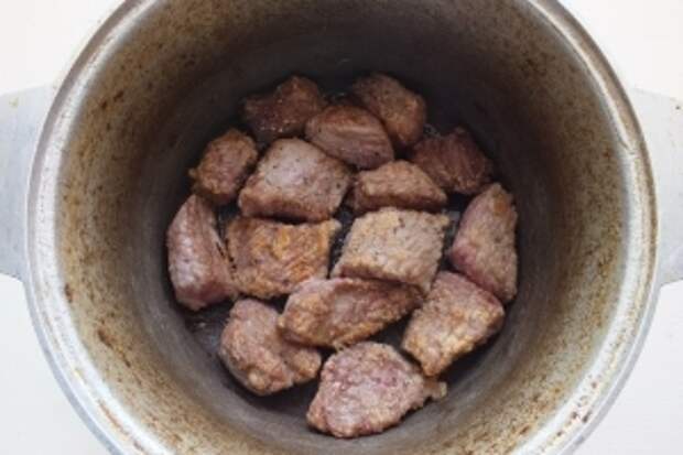 Выложите обжаренное мясо вместе с образовавшимся соком в казанок или подходящую толстостенную кастрюлю. Немного посолите и поперчите.