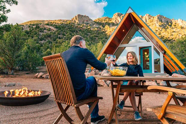 Smiling couple toasting over outdoor table.