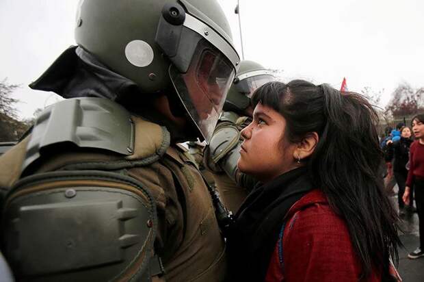 Лицом к лицу: девочка-демонстрант и полицейский на акции протеста в честь годовщины военного переворота 1973 года в Сантьяго, Чили демонстрации, женщины, кадры, общество, протест, сильные женщины, сильные фотографии, фото