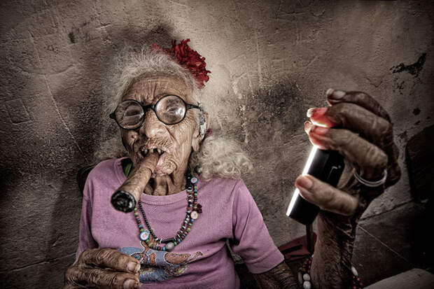 Кубинская женщина курит сигару и держит кольцевую вспышку. история, факты