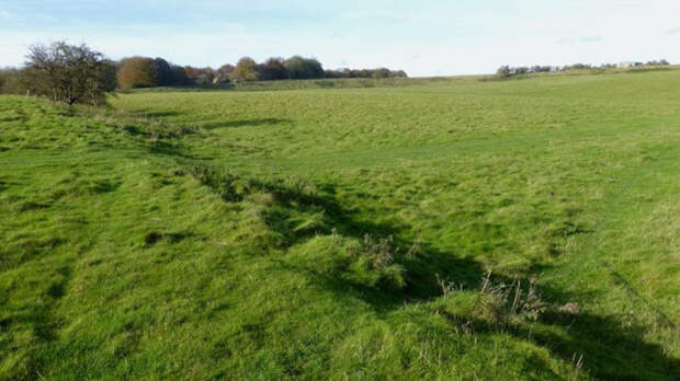 На переднем плане - южная стена Даррингтонских стен доисторического места недалеко от Даррингтона в Уилтшире. На заднем плане изображения - западная стена участка.
