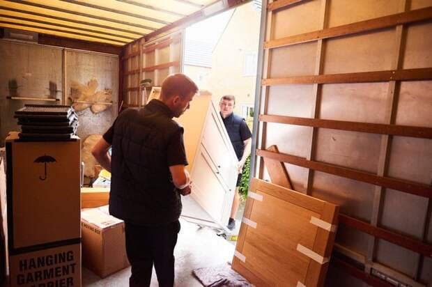 Moving company workers transport boxes and large furniture.