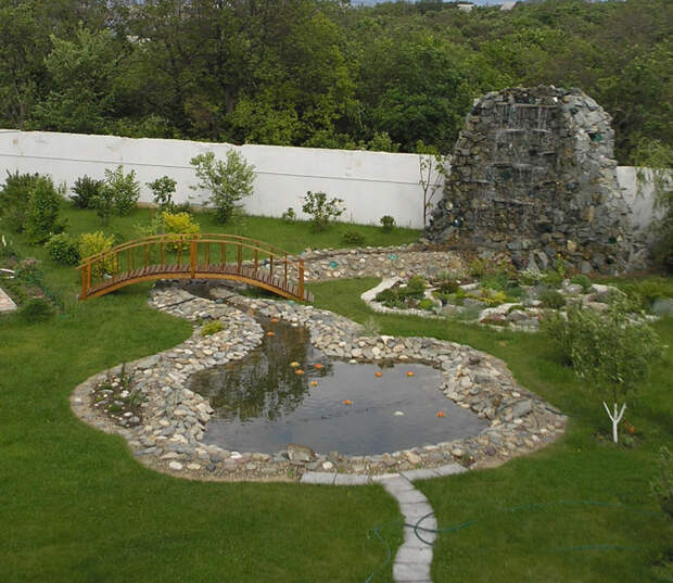Ландшафтный дизайн садового участка с прудом, классическим водопадом и небольшим деревянным мостиком. 