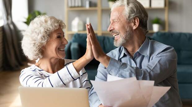 Two smiling people giving each other a high five.