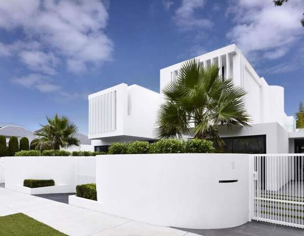 Белый металлический забор, который идеально гармонирует с архитектурным обликом загородного дома.