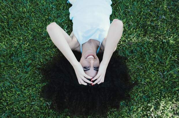 Woman in White Halter Top Laying Green Grass Field during Day Time