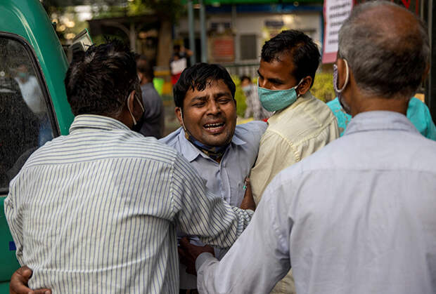 Люди оплакивают смерть родственника возле больницы в Нью-Дели