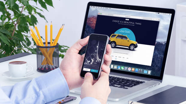Uber app on the iPhone display in man hands and Uber website on