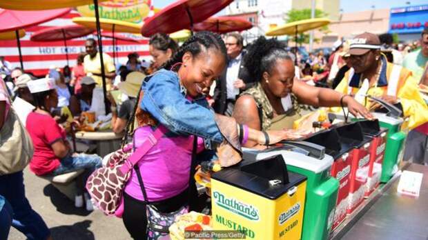 Customers work the condiments station. Coney Island's