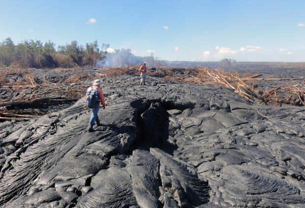 Геологи ходят по поверхности потока лавы
