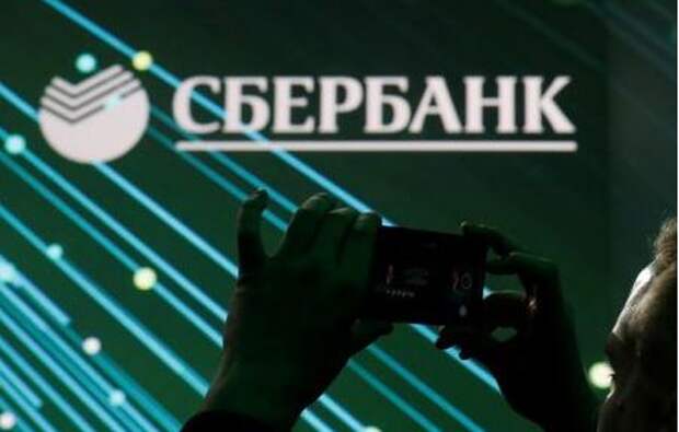 A man takes a picture of the logo of Russian bank Sberbank on a screen during a session of the St. Petersburg International Economic Forum (SPIEF), Russia June 6, 2019. REUTERS/Maxim Shemetov
