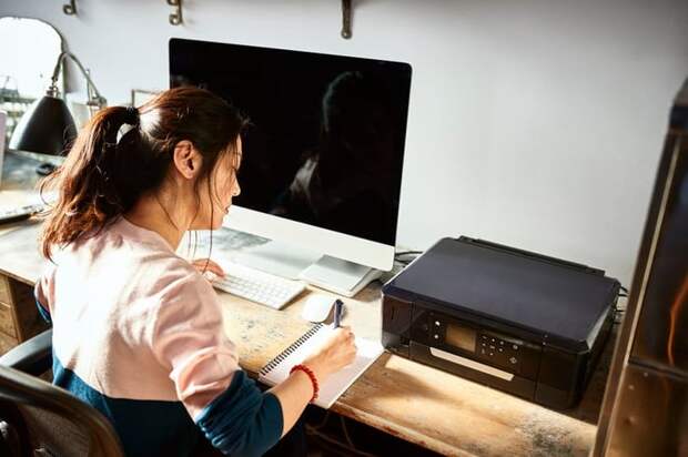 Woman writing in notebook at her home desk