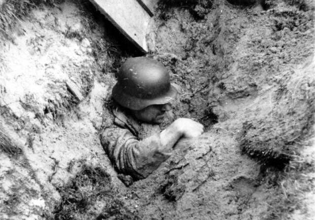 Немецкий солдат пытается выбраться из засыпанного близким разрывом окопа Великая отечественая война, архивные фотографии, вторая мировая война