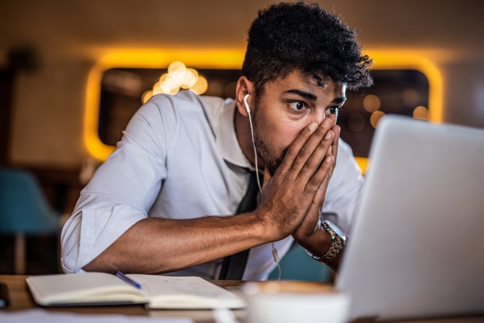 Concerned person with hands over face looking at laptop.